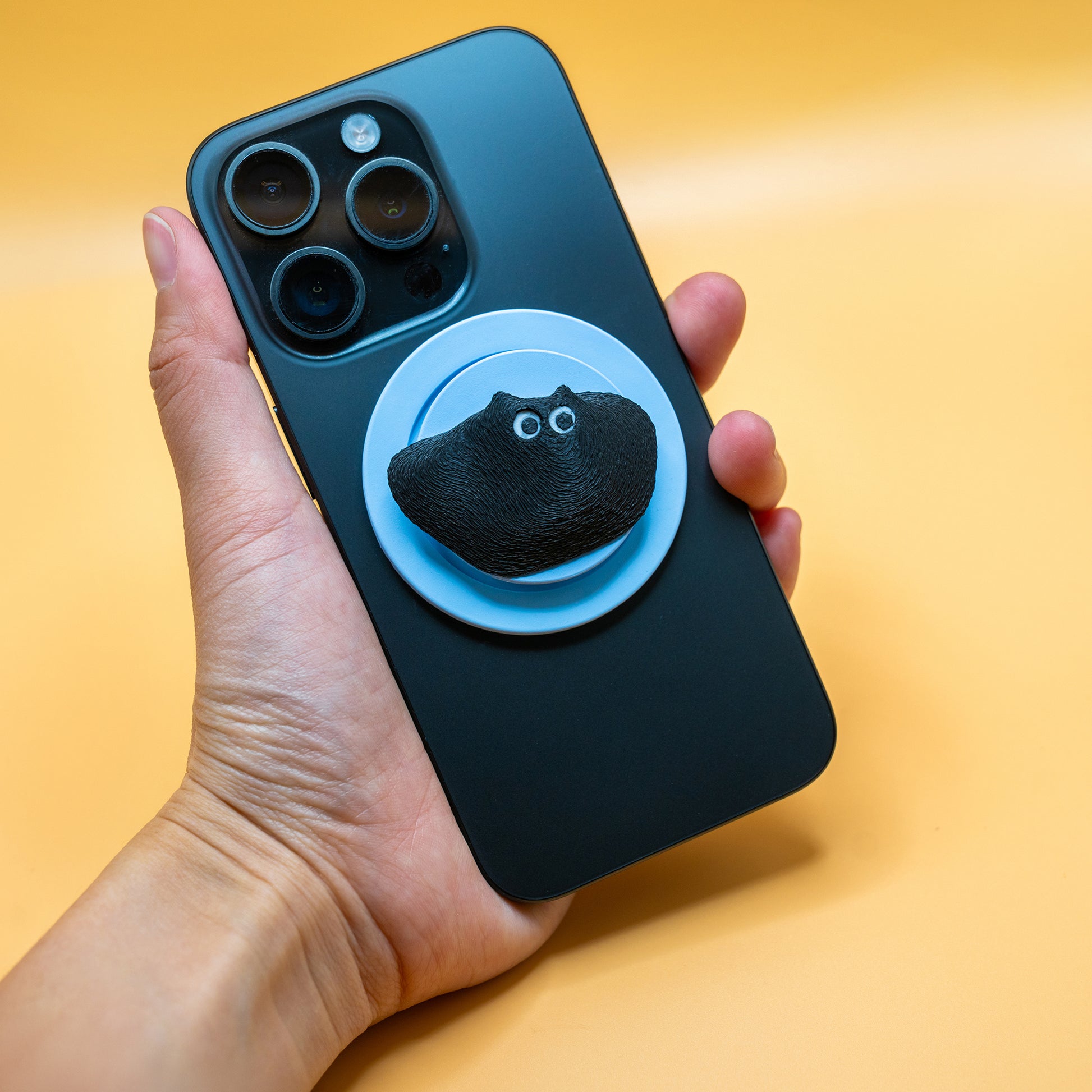 A MagSafe phone grip shaped like a climbing hold, featuring Black Meow the cat – a fun and functional gift for rock climbers and cat lovers.