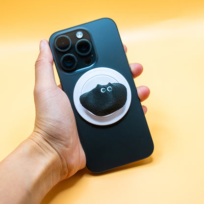 A MagSafe phone grip shaped like a climbing hold, featuring Black Meow the cat – a fun and functional gift for rock climbers and cat lovers.