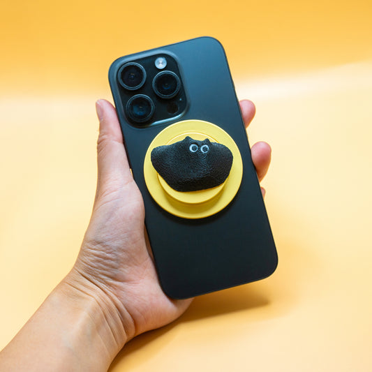 A MagSafe phone grip shaped like a climbing hold, featuring Black Meow the cat – a fun and functional gift for rock climbers and cat lovers.