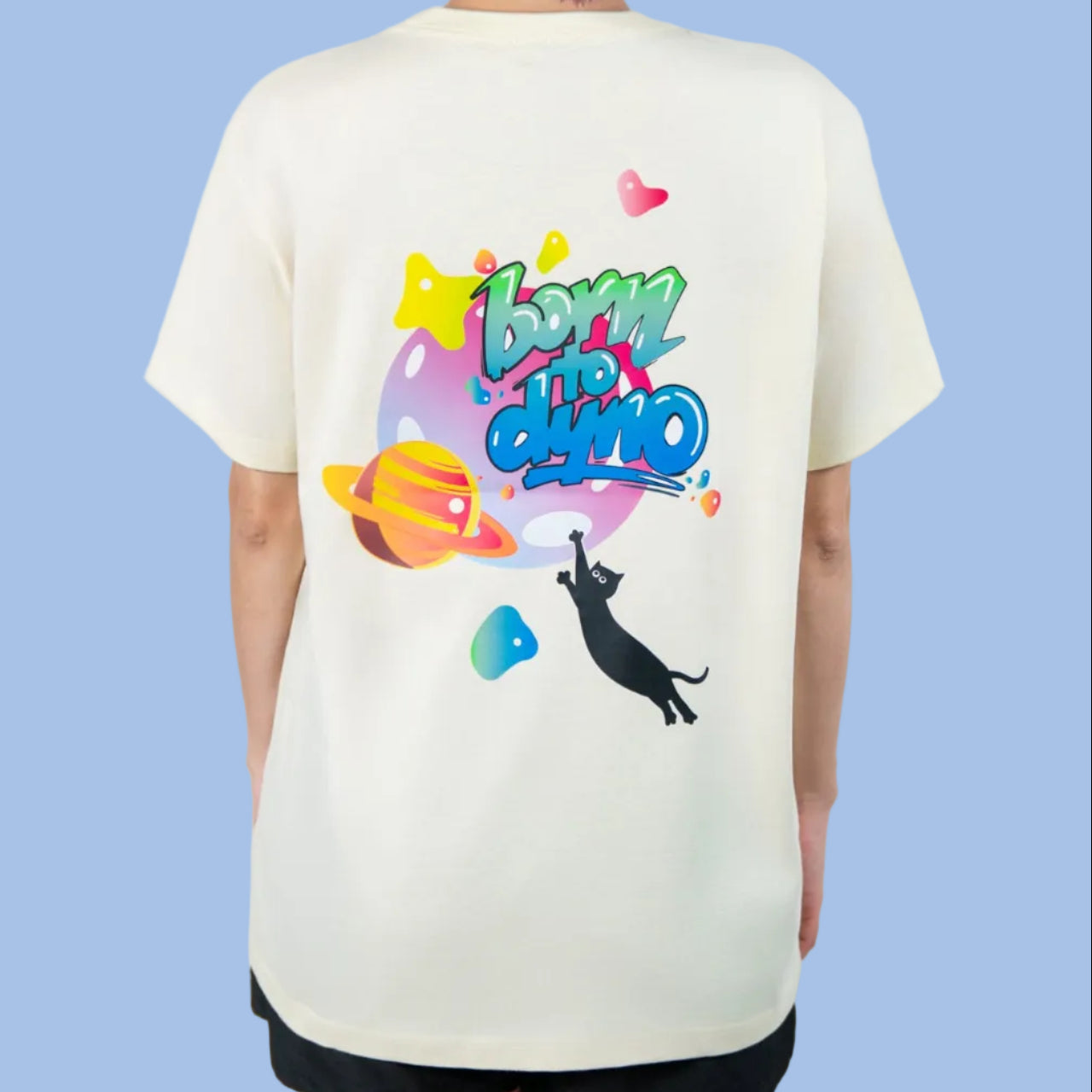 Person wearing a white t-shirt with colorful graphics and text born to dyno on the back, standing against a plain background.