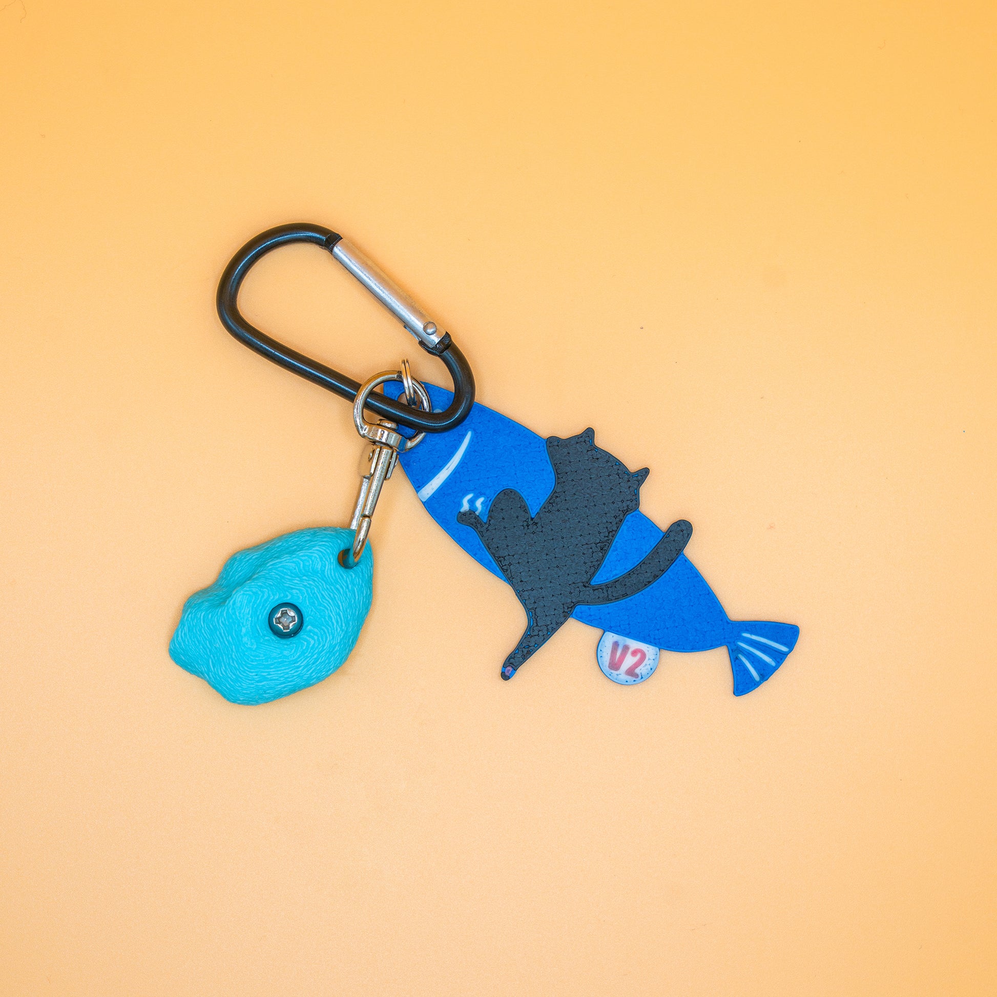 A playful V2 keychain featuring a cat climbing a fish – a fun, climbing-inspired gift for boulderers and rock climbers. Designed by Non Vertical Lab.