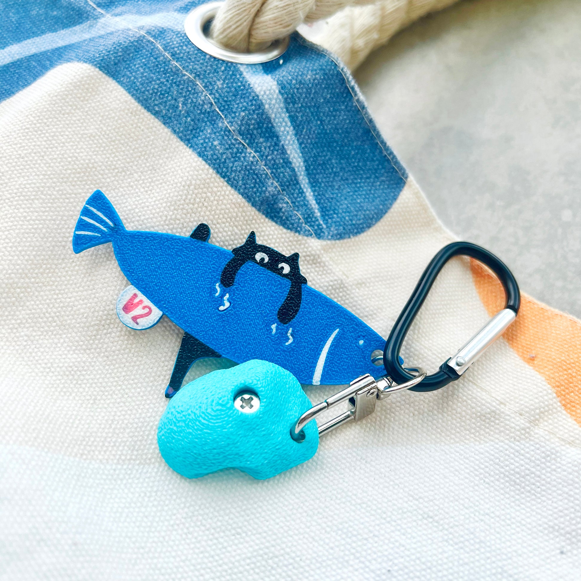 A playful V2 keychain featuring a cat climbing a fish – a fun, climbing-inspired gift for boulderers and rock climbers. Designed by Non Vertical Lab.
