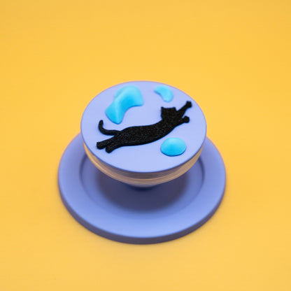 A black cat in mid-air dyno motion, leaping toward climbing holds – printed on a MagSafe phone grip. A bold gift for climbers and cat lovers. Designed by Non Vertical Lab.