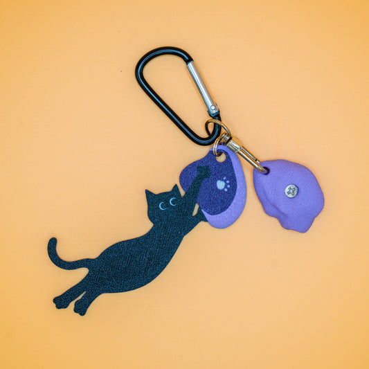 A playful cat mid-dyno on a keychain – perfect for climbers who love big moves and bold sends. Designed by Non Vertical Lab.