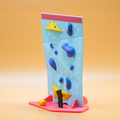 Non Vertical Lab rock climbing toy and gift – A black cat figurine gazes at a vibrant mini climbing wall with blue holds and yellow volumes. A perfect collectible for climbing enthusiasts and a fun gift for all ages.