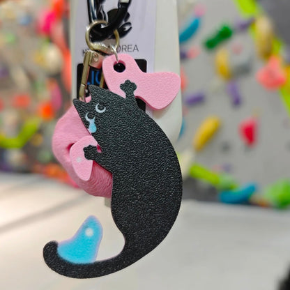 A funny short-armed cat keychain – a relatable and charming gift for climbers who know the struggle of bad reach. Designed by Non Vertical Lab.